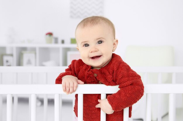 Piccolo bambino sveglio che sta nella culla a casa