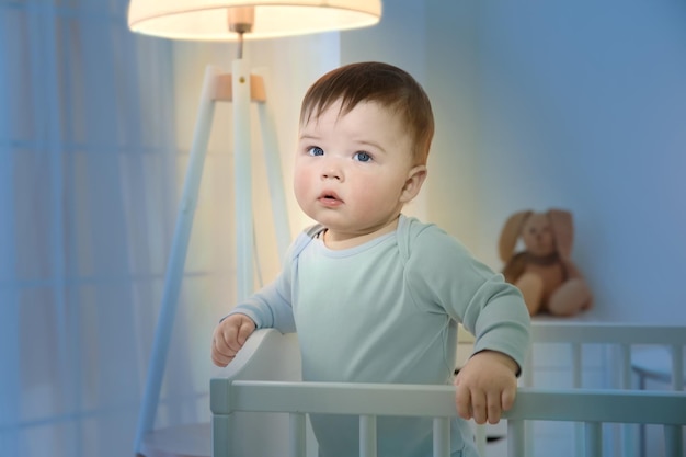 Cute little baby standing in crib at home