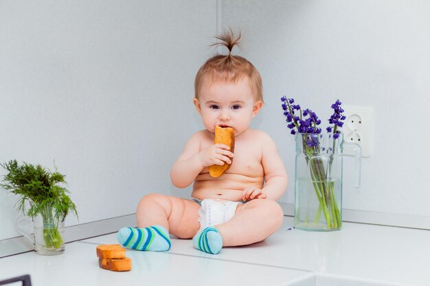 Cute little baby with cookies sitting on the table in the kitchen