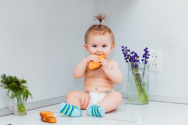 Cute little baby with cookies sitting on the table in the kitchen