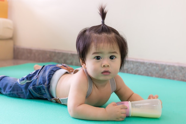 Cute little baby with tie hair enjoy playing on the floor in home