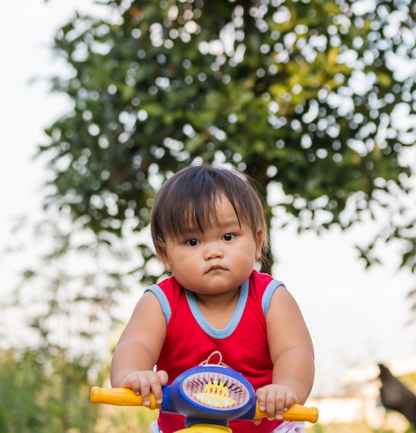 バイクと道路上のかわいい小さなバイカー。おもちゃのオートバイの少女。自然の中で最初の自転車に乗ることを学ぶ少女