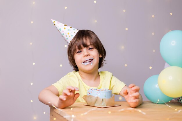 cute little birthday boy eating cake in hat balloons happy birthday