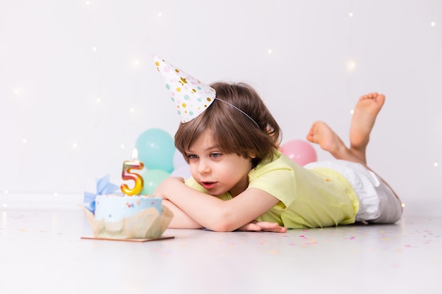 Милый маленький именинник в шляпном торте со свечой пять воздушных шаров с днем рождения