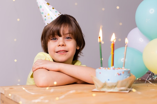 Cute little birthday boy in hat cake with candles balloons happy birthday