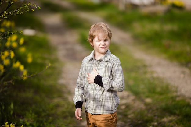 Cute little blonde boy in the spring country with yellow daffodils