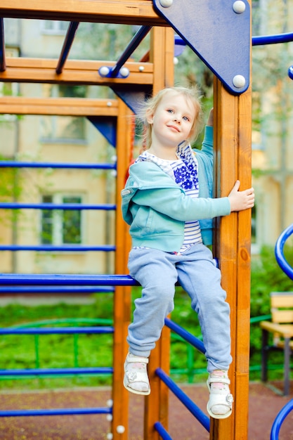 Cute little blonde caucasian girl having fun on a playground outdoors in summer. 