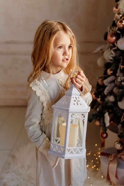 Cute little blonde girl in dress near Christmas tree