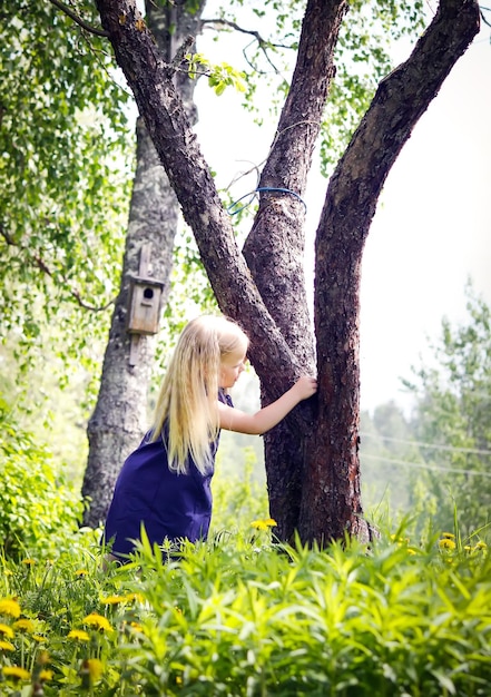 Cute little blonde girl on the meadow in summer park