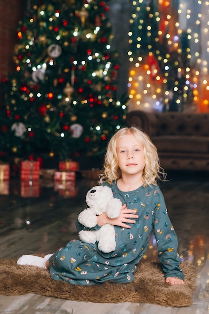 Cute little blonde girl posing at the Christmas tree