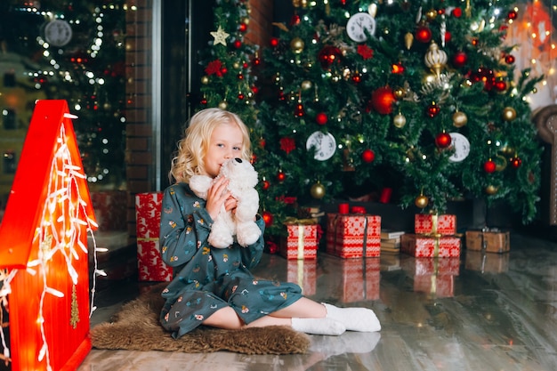 Cute little blonde girl posing at the Christmas tree