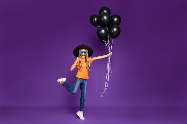 Cute little blonde girl with a witch hat and balloons