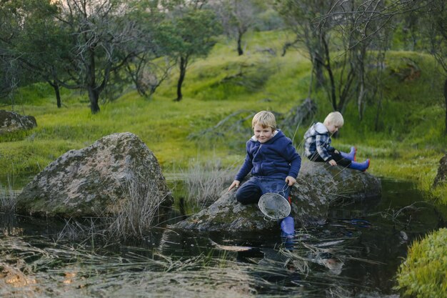 Cute little blonde kids sitting on a rock in a park