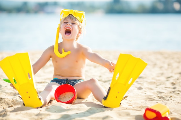 ビーチでかわいい男の子。海岸線で楽しんでいる子供。水の近くで楽しんでいる愛らしい子供。