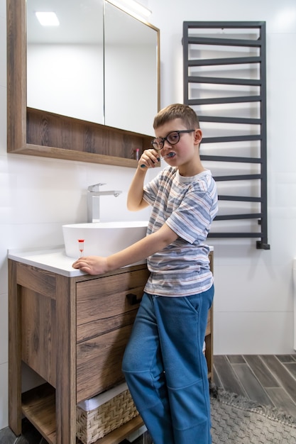 A cute little boy brushing his teeth and timing the hour with an hourglass.