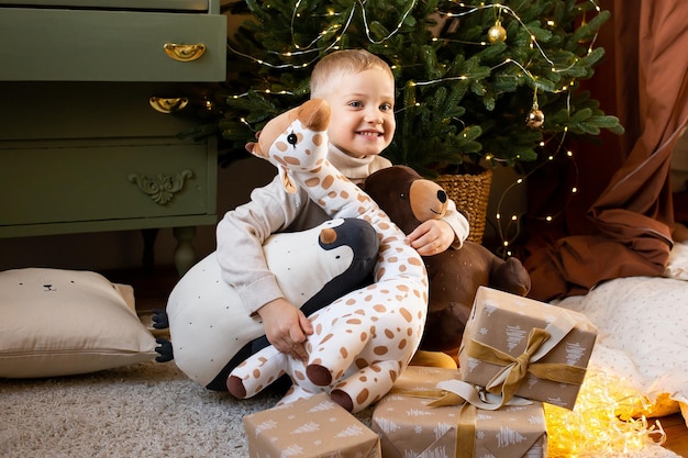 Foto ragazzino sveglio nella casa di natale vicino a una ghirlanda festiva vicino a giocattoli carini