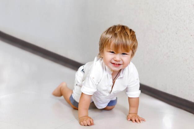 Cute little boy crawls on the floor at home and smiles