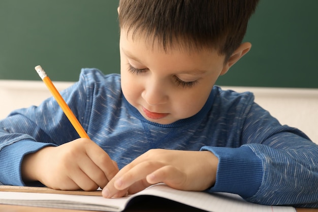 Cute little boy doing homework in classroom