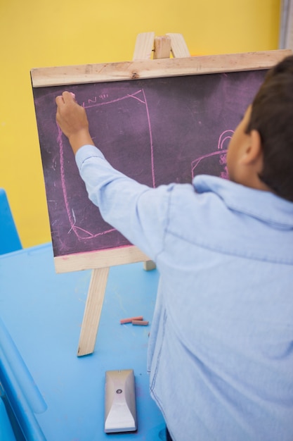 Photo cute little boy drawing on chalkboard