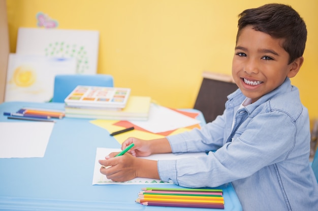 Cute little boy drawing at desk