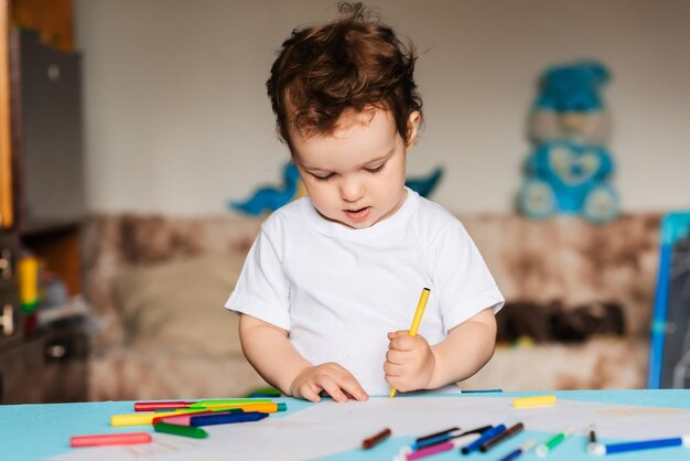 Foto un ragazzino carino disegna nel suo quaderno di disegni con matite colorate