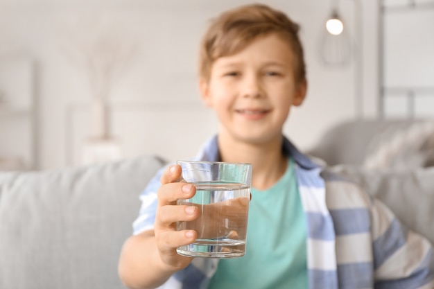 Cute little boy drinking water at home