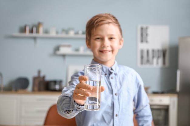 Cute little boy drinking water in kitchen