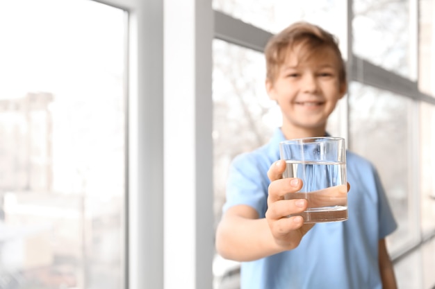 窓の近くで水を飲むかわいい男の子