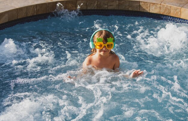 Cute little boy in funny sunglasses in pool in sunny day