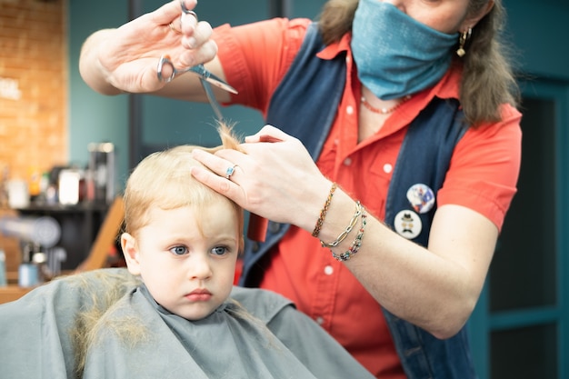 Cute little boy getting the first haircut in barbershop