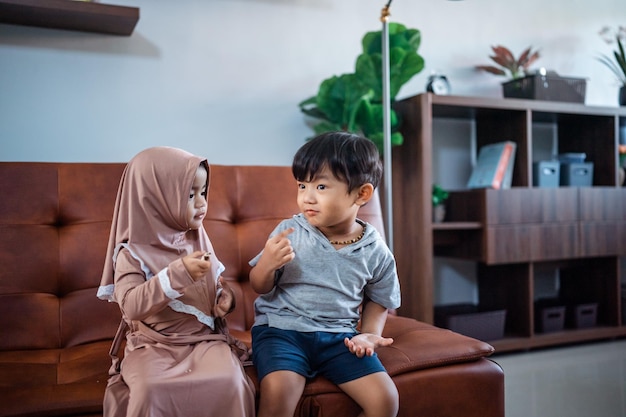 Cute little boy and girl sitting on sofa together in livingroom