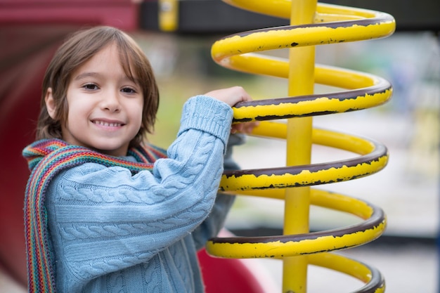 cute little boy having fun in playground park on cludy autum day