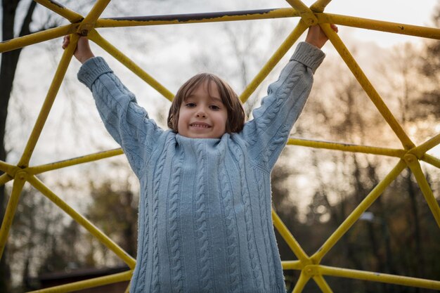 cute little boy having fun in playground park on cludy autum day