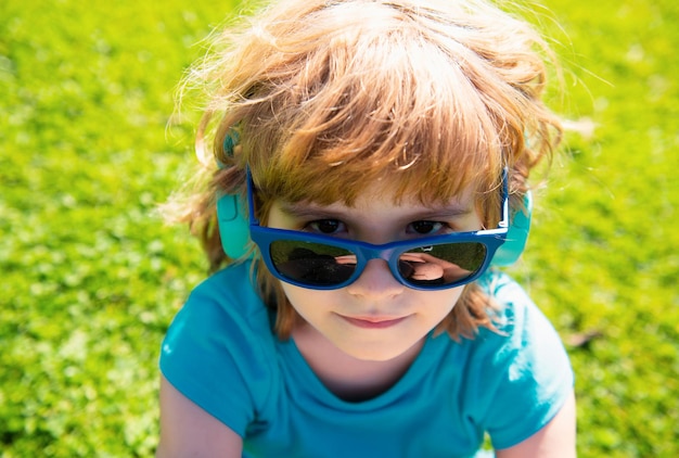 Cute little boy in headphones listening to music on color background