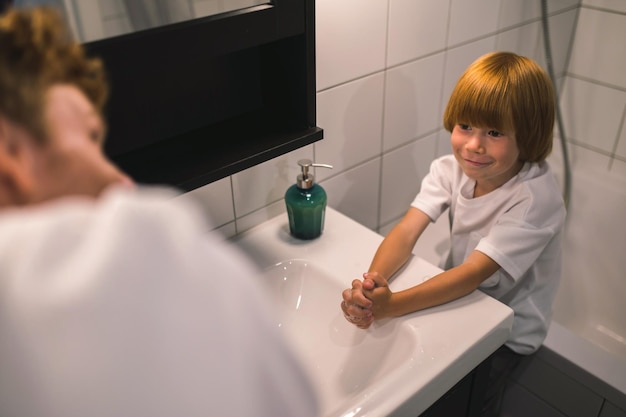 Photo cute little boy and his dad washing hands in the bathroom