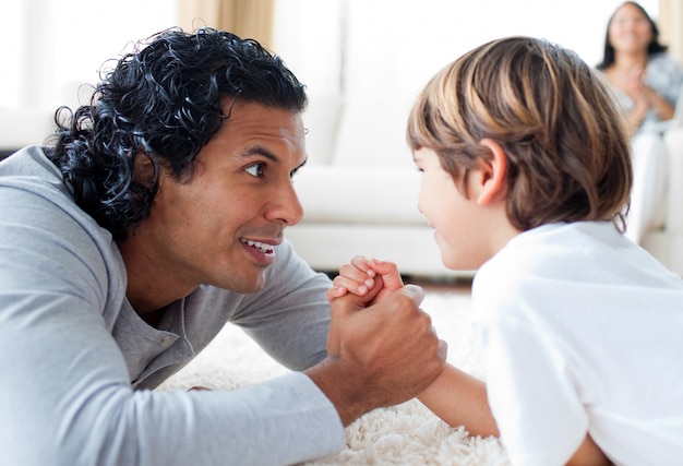 Photo cute little boy and his father armwrestling