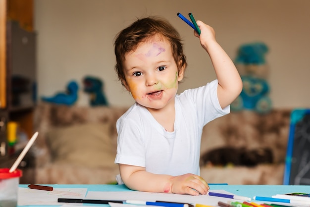 Cute little boy holding colored pencils and markers