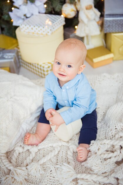 写真 スタジオでかわいい男の子。クリスマスプレゼントのそばに座っている子供