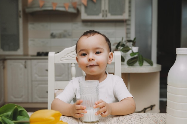 かわいい男の子がキッチンの牛乳瓶モーションキャプチャのテーブルで牛乳を飲んでいます