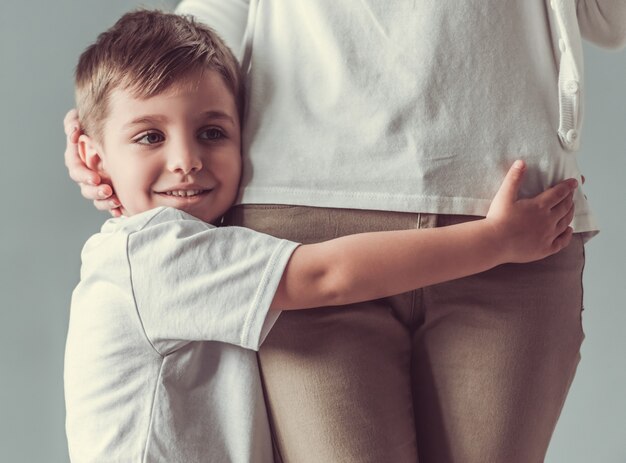 Cute little boy is hugging his mom and smiling.