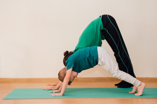 Cute little boy is learning to do yoga in the gym