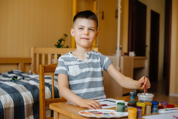 A cute little boy is playing and painting in his room. Recreation and entertainment. Stay at home.