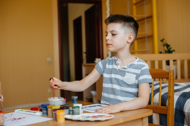 A cute little boy is playing and painting in his room. Recreation and entertainment. Stay at home.