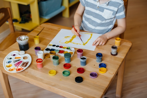 A cute little boy is playing and painting in his room. Recreation and entertainment. Stay at home.