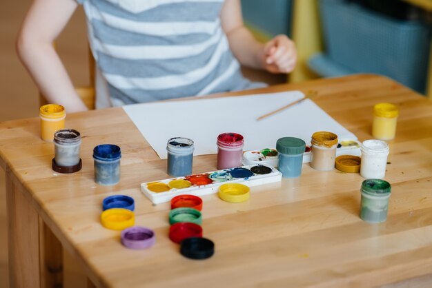 A cute little boy is playing and painting in his room