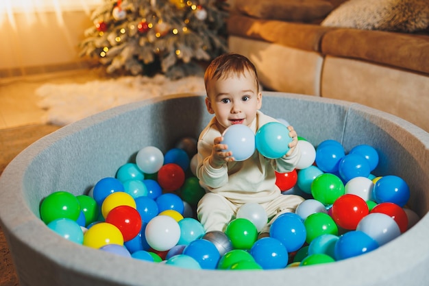 可愛い小さな男の子がプラスチックボールのプールで遊んでいる ⁇ 子供の乾燥プールが家にある