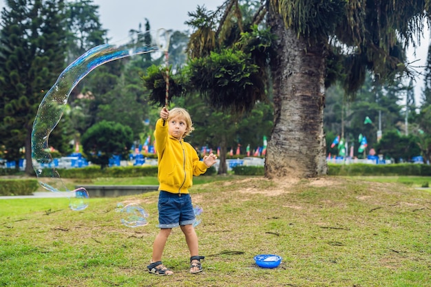 Cute little boy is playing with big bubbles outdoor