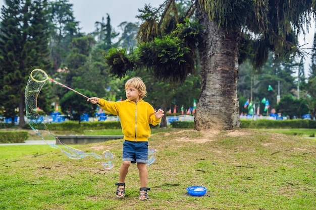 Cute little boy is playing with big bubbles outdoor