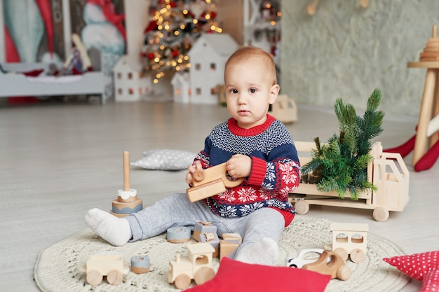 Cute little boy is playing with toy wooden train, toy car, pyramid and cubes, learning development concept. Development of kids fine motor skills, imagination and logical thinking