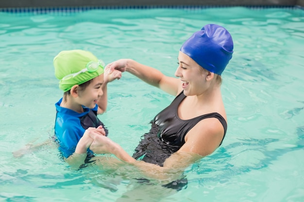 Cute little boy learning to swim with coach